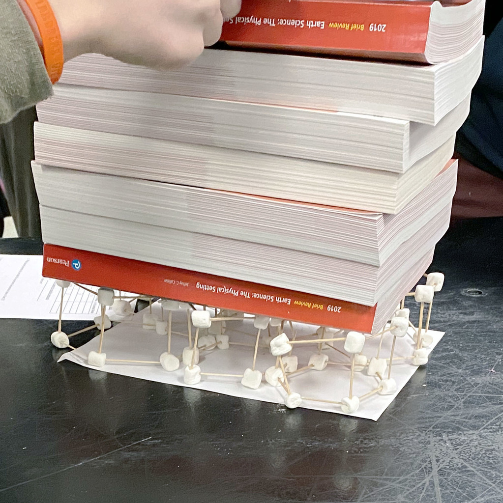 A structure made of marshmallows and toothpicks supporting textbooks