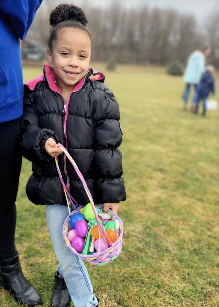 A child poses with her basket of eggs