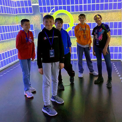 Students pose for a photo in a room depicting solar panels