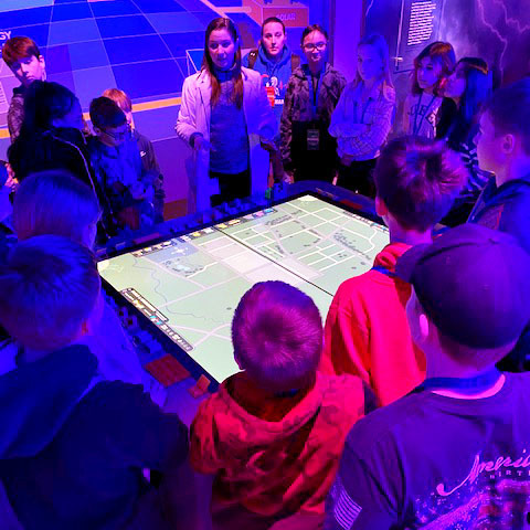 Students gather around a table with a map
