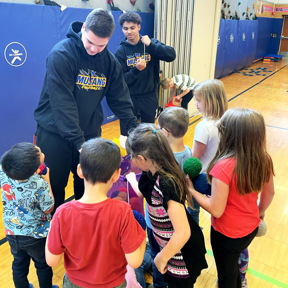 Football players volunteer with elementary students
