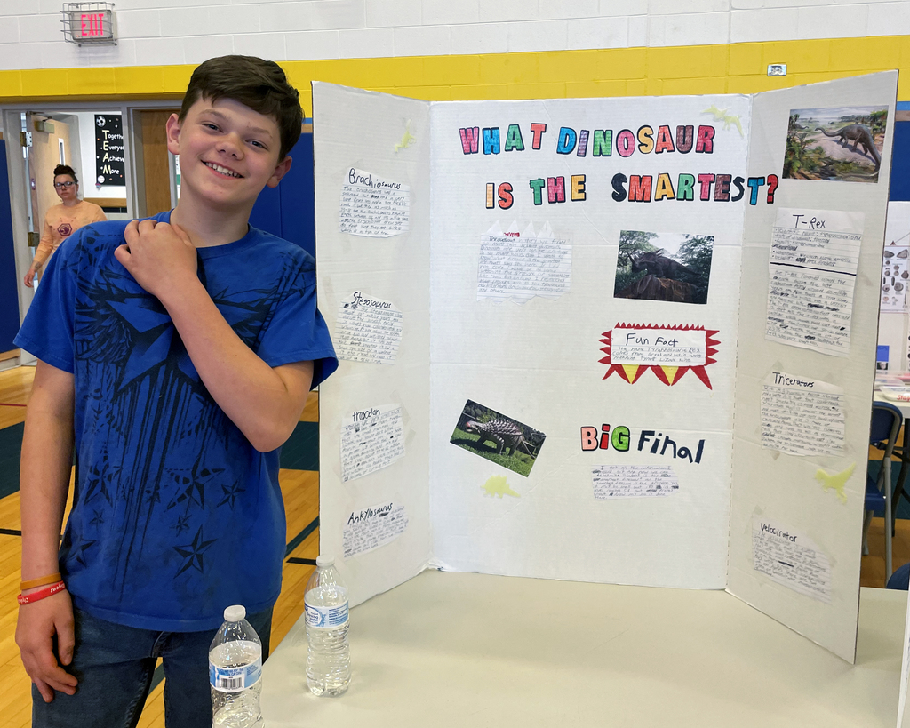 Student stands in front of trifold on dinosaurs
